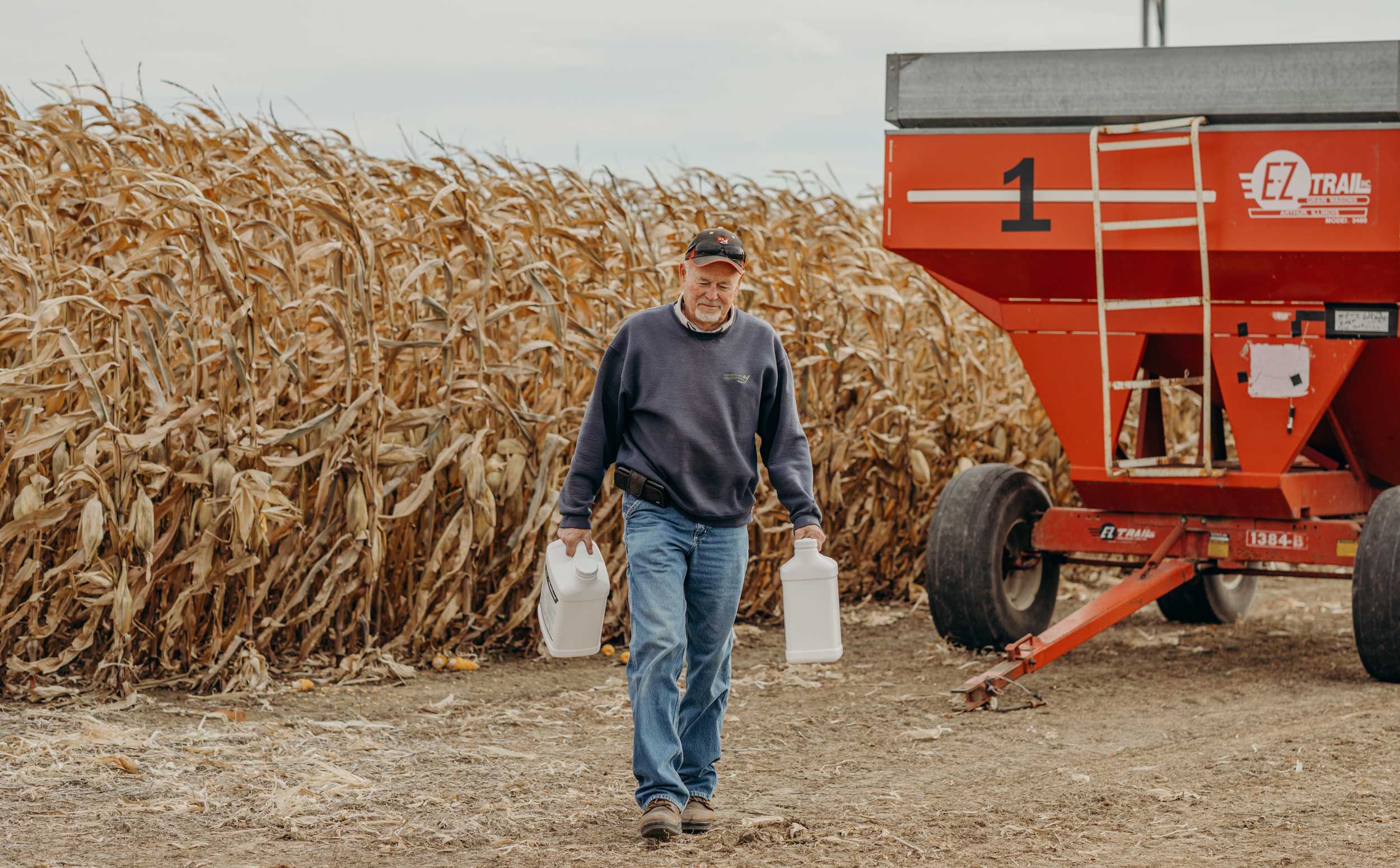 Farmer near crops carrying plastic jugs